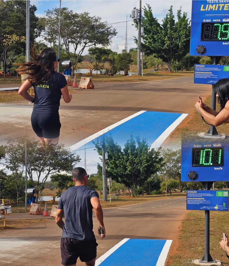 Painéis eletrônicos mostrando velocidades de 7.9 km/h e 10.1 km/h enquanto atletas correm na pista azul do Estacionamento 10 no Parque da Cidade.