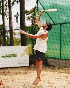 Atleta saltando na areia para dar um corte durante partida de Beach Tennis na Club.Co em Brasília.